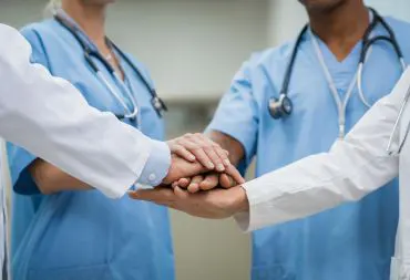Healthcare professionals handling sealed medical waste containers in a Cardiff hospital